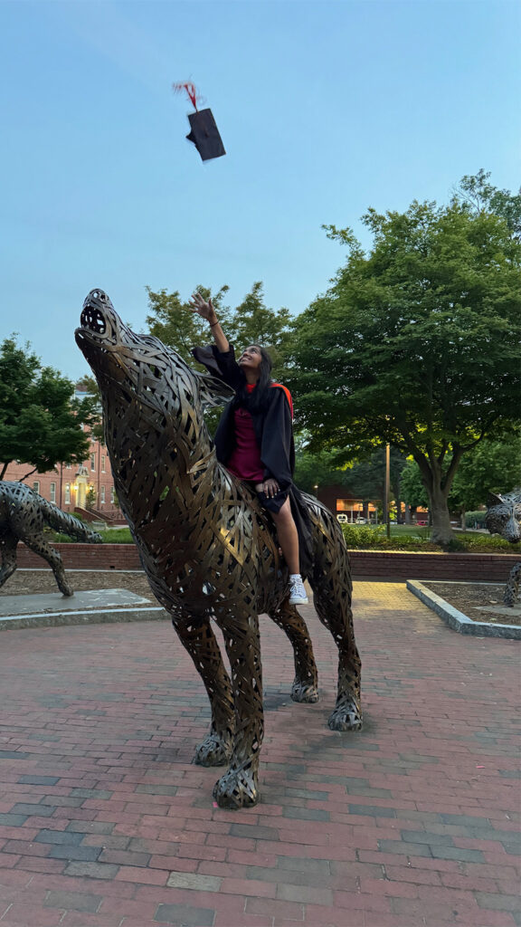 Amy Deepee sits atop one of the bronze wolves at NC State University.