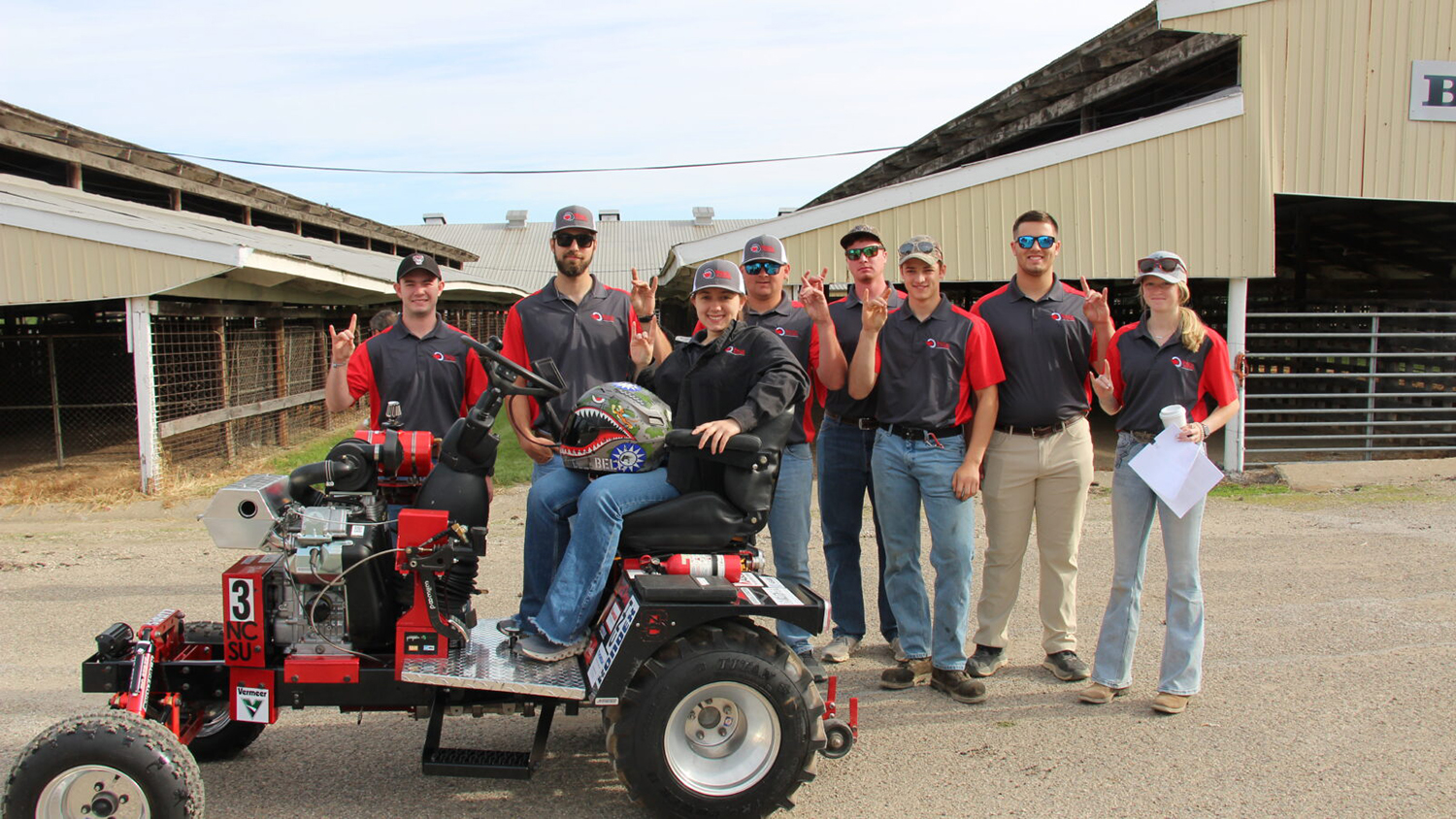 The NC State "Pack Pullers" pose as a group with their tractor.