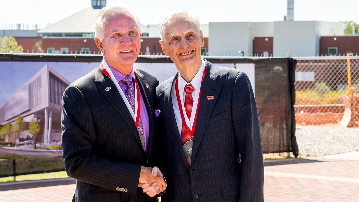 Ed Woolard, right, shakes hands with Ed Fitts at the groundbreaking for Fitts-Woolard Hall.