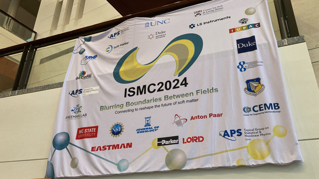 Photo from the International Soft Matter Conference 2024 showing a large hanging banner with the conference logo and logos of conference sponsors.