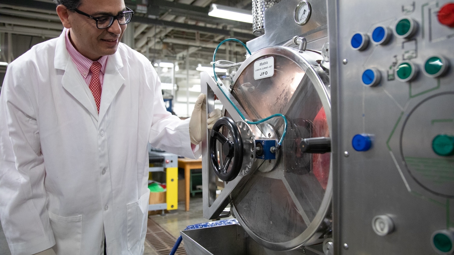 Ahmed El-Shafei stands to left of a machine in the Pilot Plant.