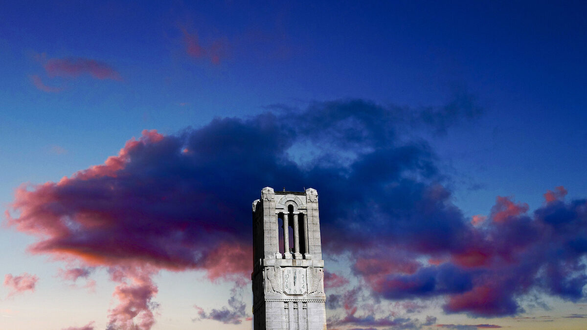 nc state university belltower silhouetted against a sunset