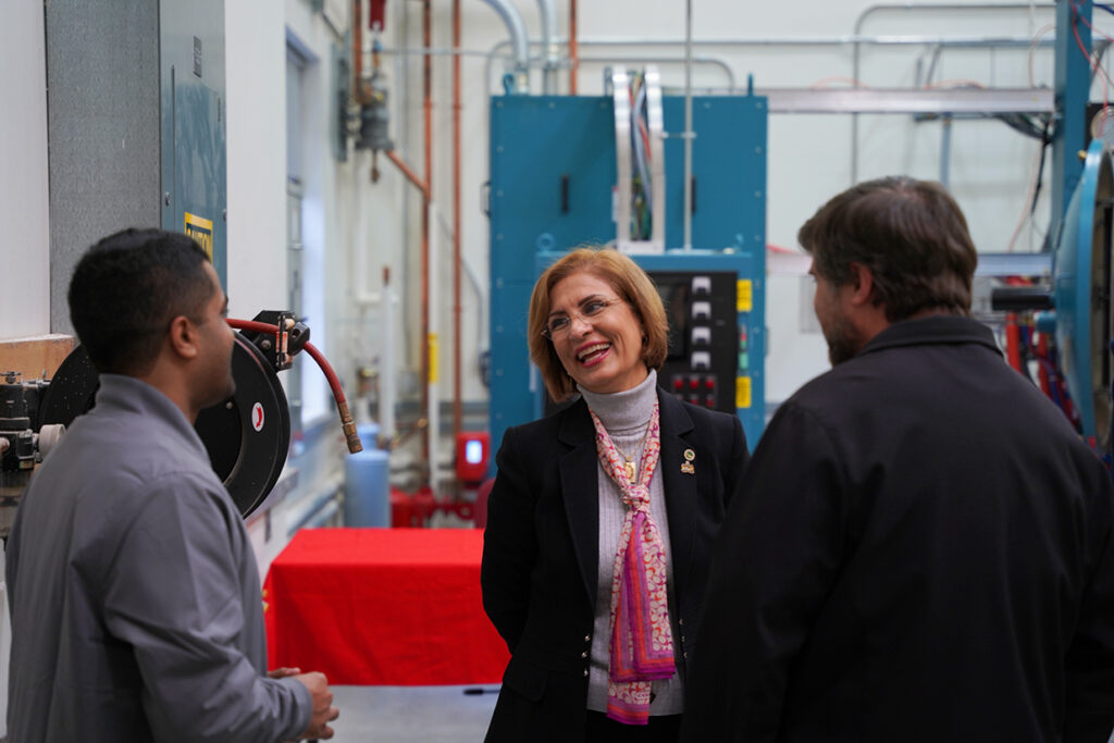 Afsaneh Rabiei, center, shares a laugh with a group of visitors at the Hot Press Furnance facility.