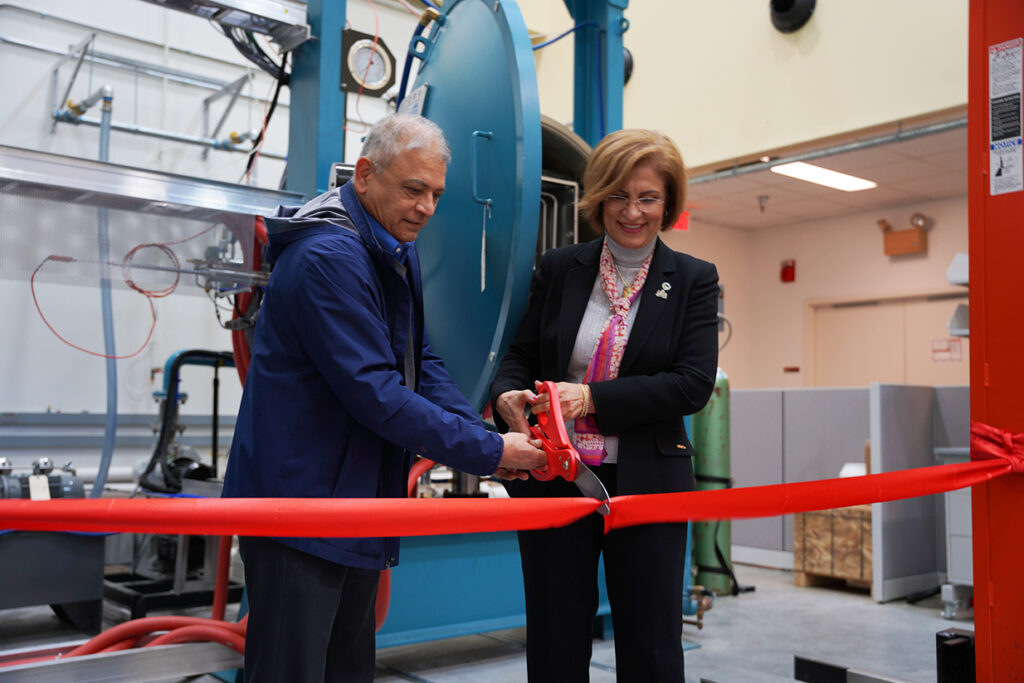 Afsaneh Rabiei, right, and MAE department head Srinath Ekkad, left, cut a red ribbon to celebrate the opening of the new Hot Press Furnace facility on NC State University's Centennial Campus.