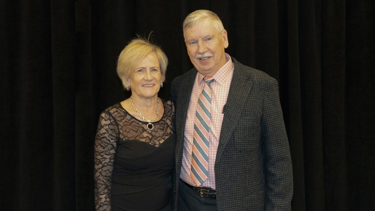Susie and Russ O'Dell at the CBE Centennial Alumni Weekend Gala in March 2024. They are standing in front of a black background.