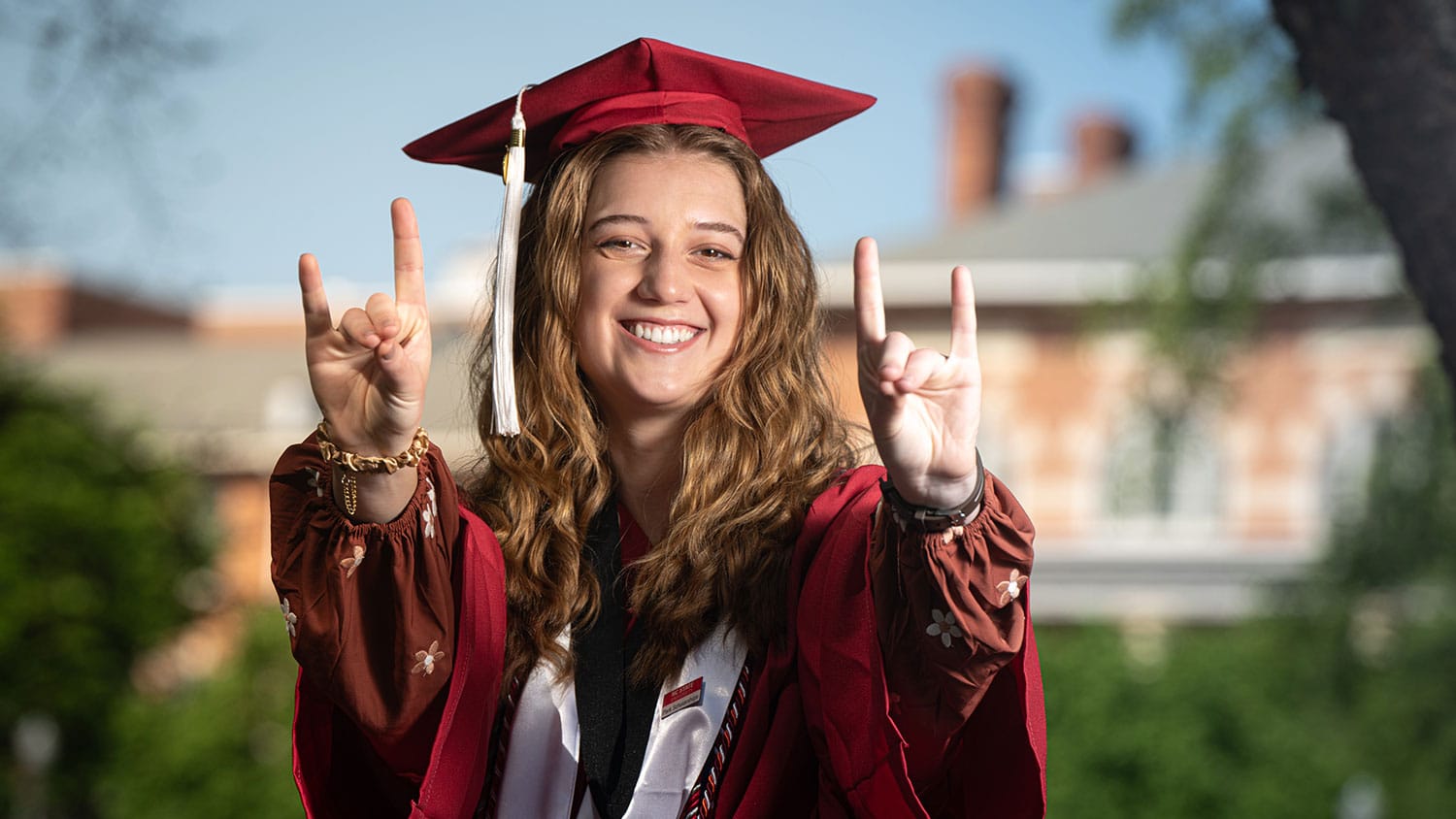 "Emi Boldor, a spring 2025 NC State graduate, poses in cap and gown in the leadup to commencement."