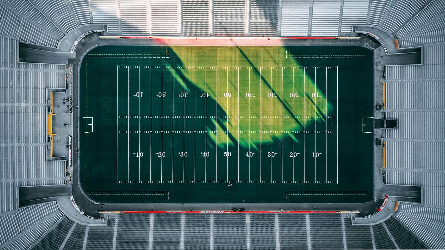 aerial view of a football field in a stadium. all distinguishing features, such as logos, have been removed from the field and stadium