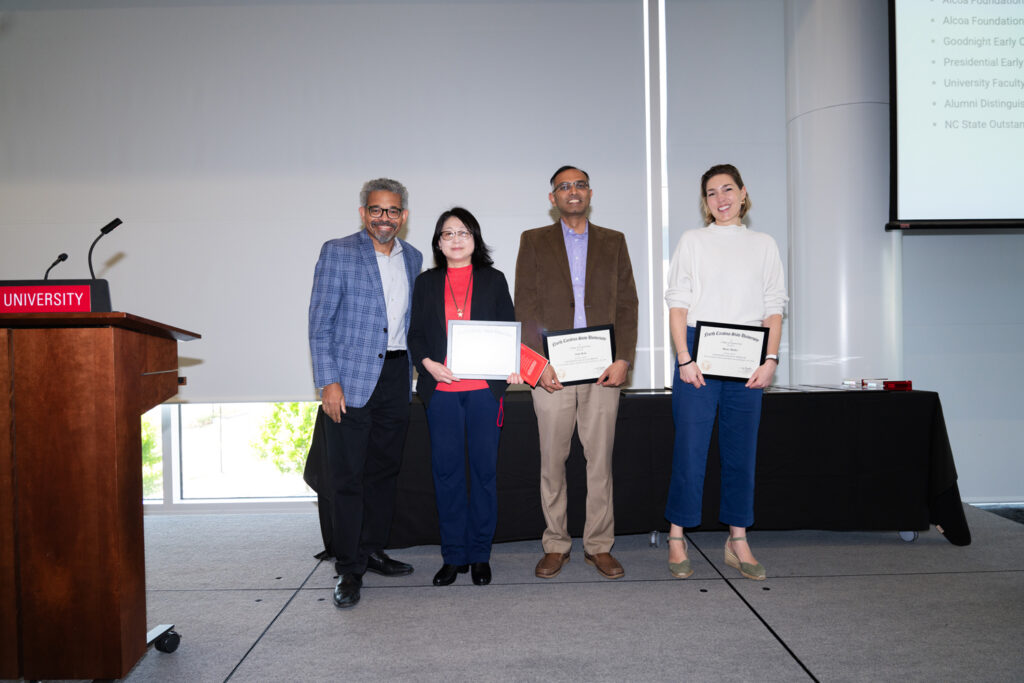 Group of faculty pose for a group photo during an awards ceremony.
