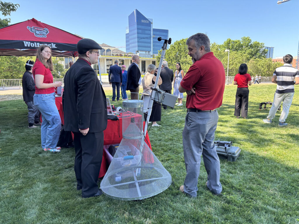 Assistant Research Professor James Reynolds talks to attendees about a new device used to trap and count moths.