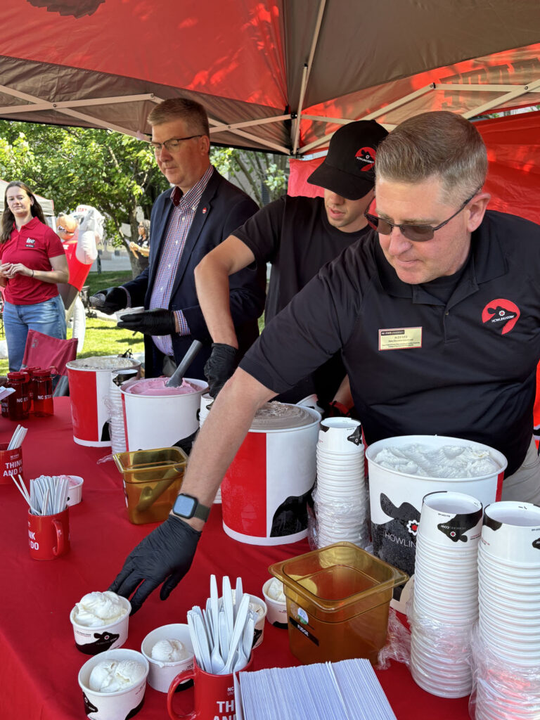 Howling Cow employees serve ice cream under a red canopy