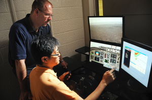 Dave Kaber looks over a graduate student's shoulder as they test flight simulator in Daniels Hall.
