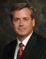 man wearing a dark suit, white shirt and red necktie