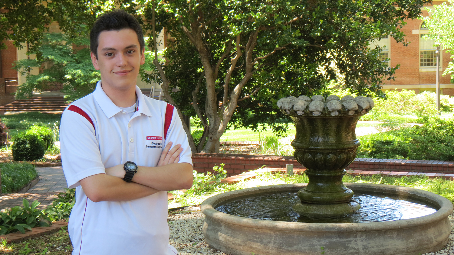 Ryan Unger standing by a fountain with his arms crossed