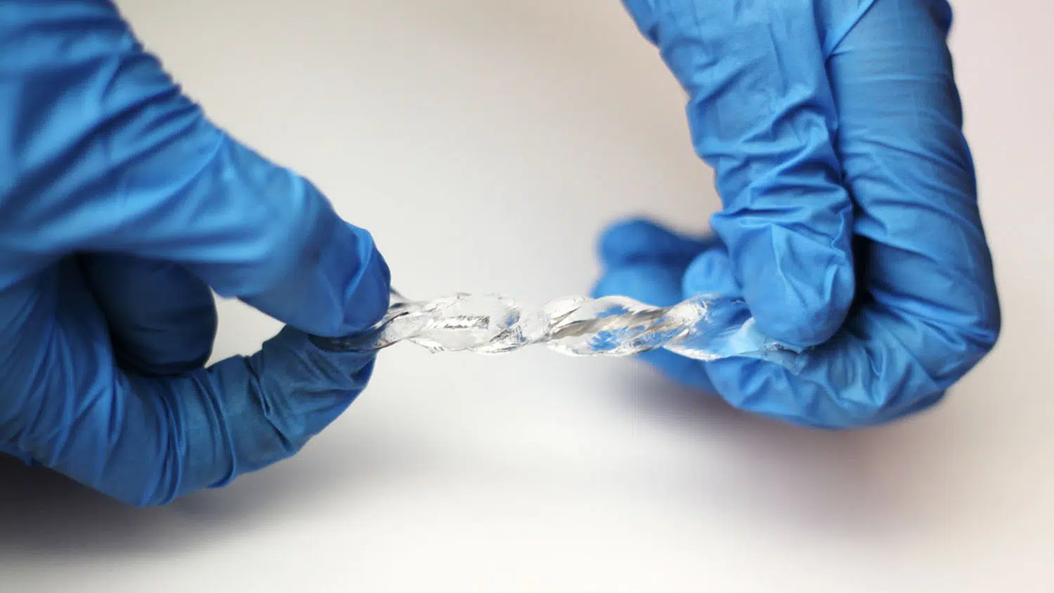 Blue latex gloved hand holding a piece of liquid metal.