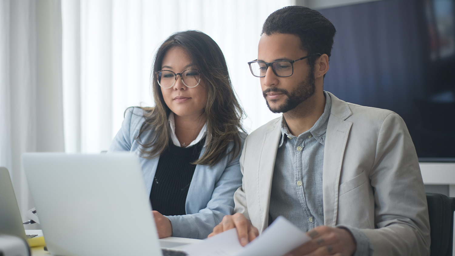 A woman and man collaborate at a computer.