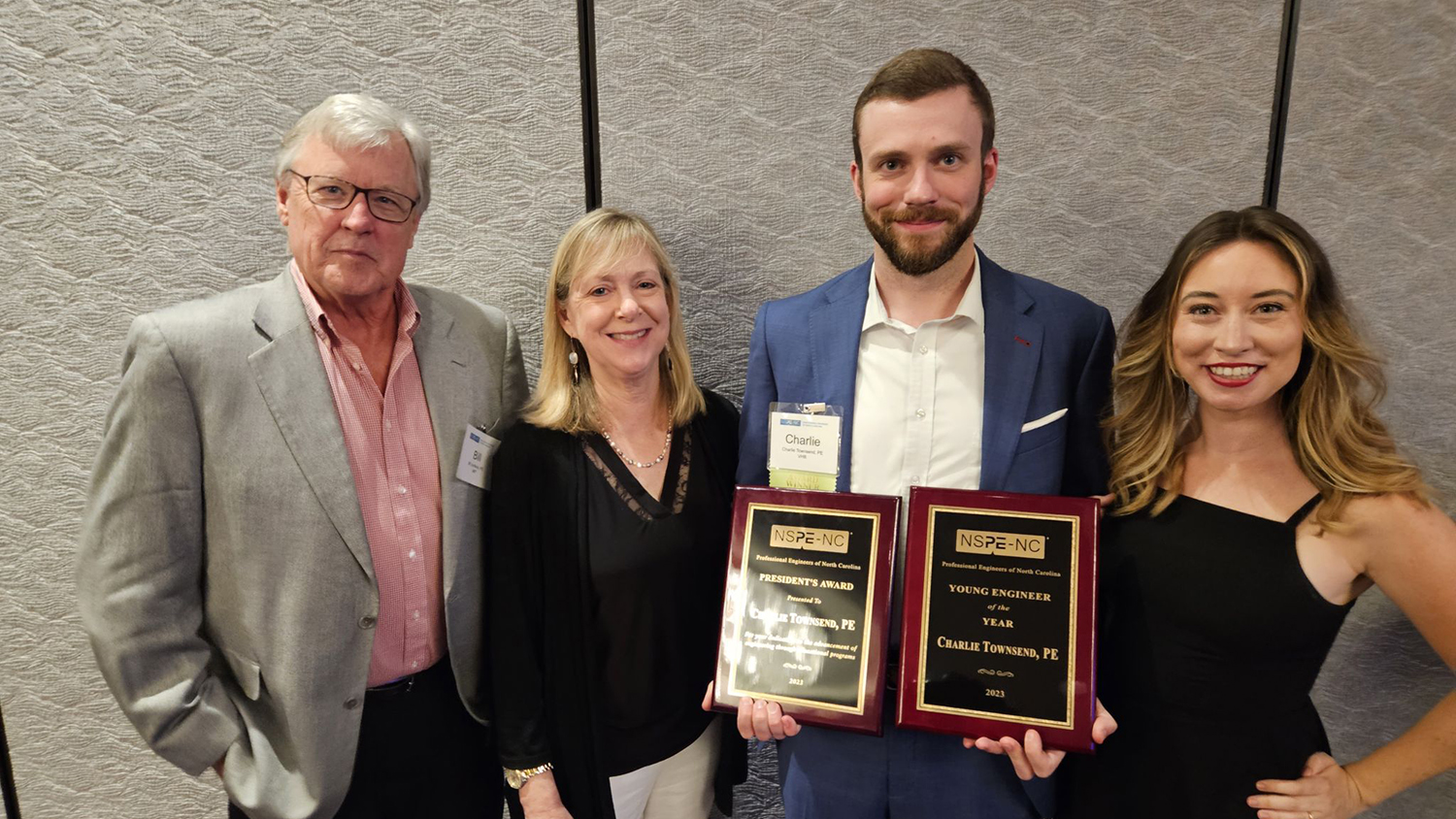 Charles Townsend, second from right, holds two awards. He is joined by three other people, two to his right and one to his left.