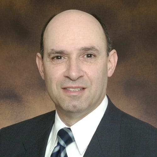 man wearing a dark suit and tie with white dress shirt
