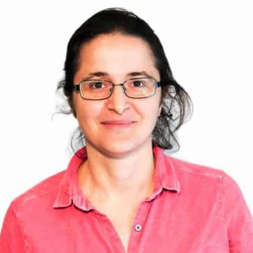 woman with long dark hair, wearing glasses, and a pink top