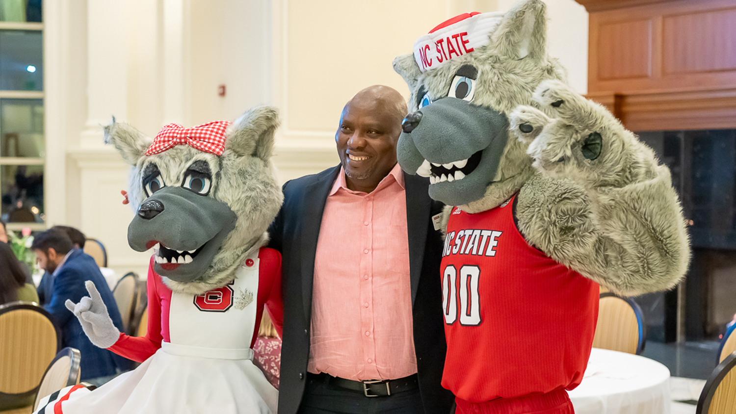 Martin Thou, center, flanked by the university mascots, Mr. and Mrs. Wuf smiles for a photo at a public event.