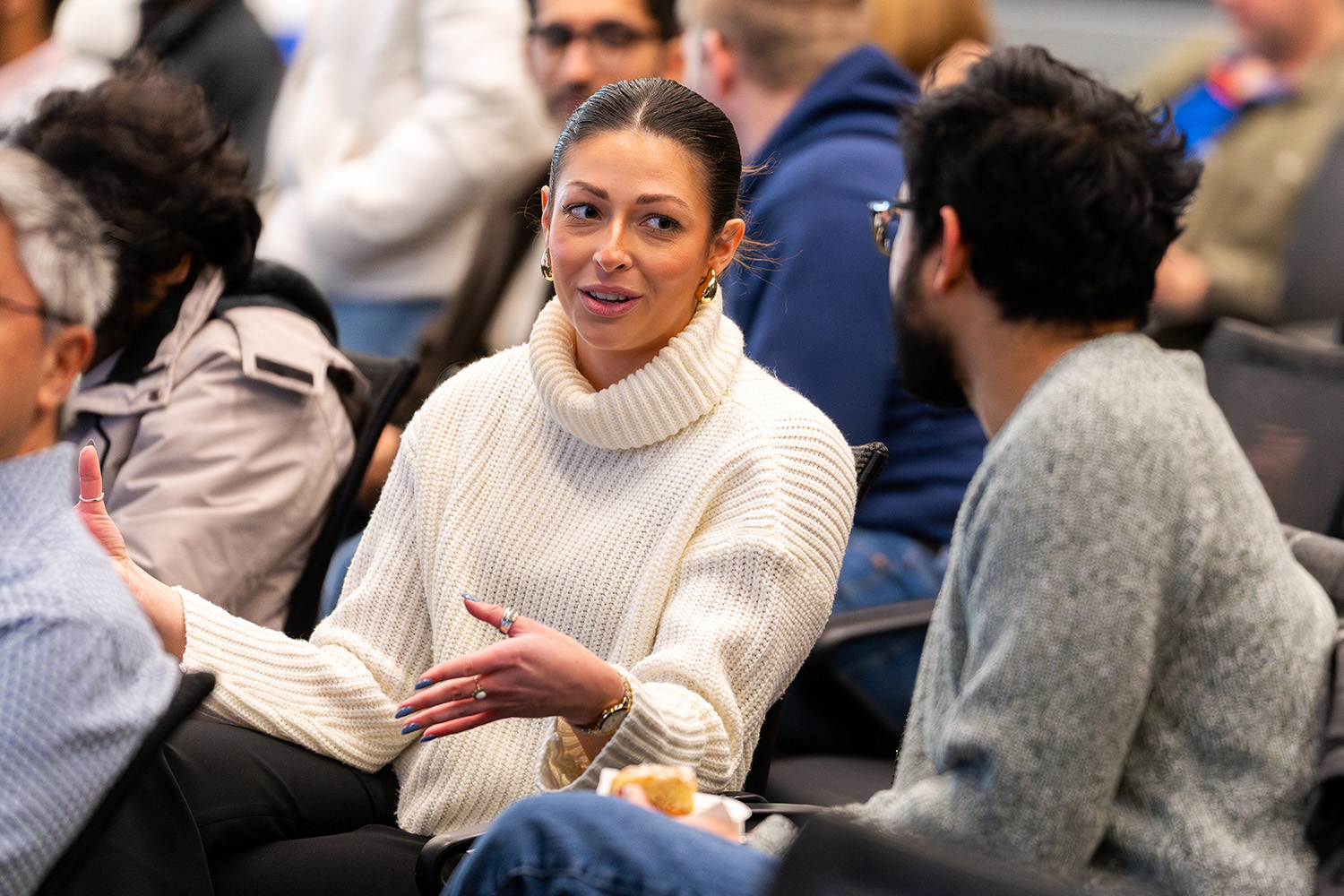 woman with pulled back dark hair talking with a man to her left